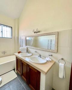 La salle de bains est pourvue de 2 lavabos, d'un miroir et d'une baignoire. dans l'établissement Villa Macheo, à Mombasa