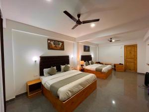 a bedroom with two beds and a ceiling fan at Riverdale Resort, Manali - A Riverside Resort in Manāli