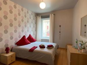 Un dormitorio con una cama con almohadas rojas y una ventana en Maison Gecko, en Ornaisons