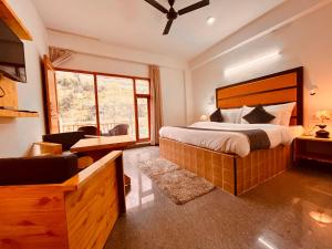 a bedroom with a large bed and a desk at Riverdale Resort, Manali - A Riverside Resort in Manāli