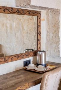 a mirror on a wooden table with a tea kettle at Uzay Cave Suite Hotel in Ürgüp