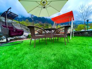 a group of chairs and an umbrella on a lawn at Riverdale Resort, Manali - A Riverside Resort in Manāli