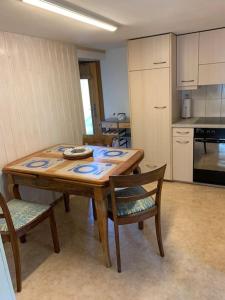 Cosy apartment in heritage protected swiss chalet في ماتين: مطبخ مع طاولة وكراسي خشبية في الغرفة