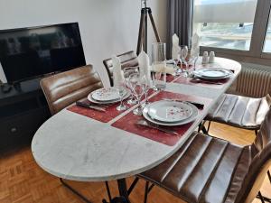- une table à manger avec des assiettes et des verres à vin dans l'établissement Sous les Etoiles - dans le plus haut gratte-ciel avec parking, à Rouen
