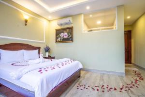 a bedroom with a bed with white sheets and red flowers at Sea Memory Hotel in Vung Tau