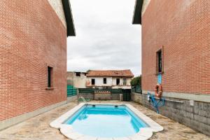 a swimming pool in the middle of two brick buildings at La Solana de Boo in Boó de Piélagos