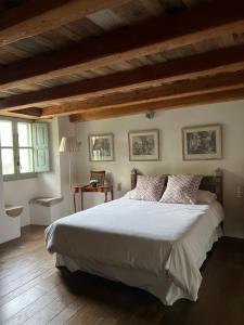 Schlafzimmer mit einem großen weißen Bett und Holzdecken in der Unterkunft Bartró de Orfans in Orfes