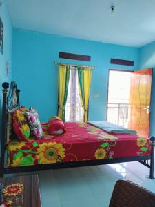 Cowang Dereng Home Stay في لابوان باجو: غرفة نوم بها سرير كبير وعليه زهور