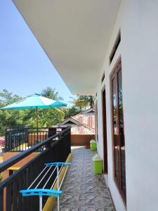 a balcony with two benches and an umbrella at Cowang Dereng Home Stay in Labuan Bajo