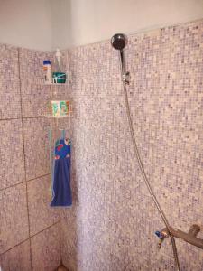 a shower with a blue towel on a tiled wall at Cowang Dereng Home Stay in Labuan Bajo