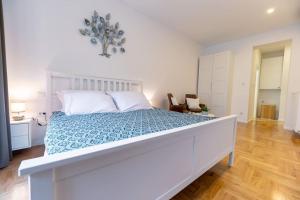 a white bedroom with a large bed with a blue bedspread at Petra - Official 4* One Bedroom Apartment-Balcony in Zagreb