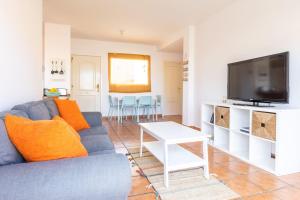 a living room with a blue couch and a tv at Garden house with two terraces in Corralejo