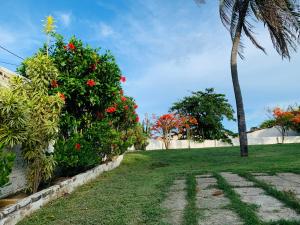 a palm tree and a green yard with red flowers at Morro Branco Suítes - HMB in Beberibe