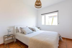 a bedroom with a large white bed with a window at Garden house with two terraces in Corralejo +14 photos