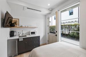 a bedroom with a bed and a kitchen with a window at Casa Jardin - Boutique Suites in Downtown Santa Barbara in Santa Barbara