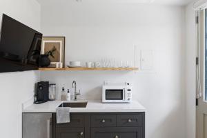 uma cozinha com um lavatório e um micro-ondas em Casa Jardin - Boutique Suites in Downtown Santa Barbara em Santa Bárbara