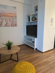 - un salon avec une télévision et une table dans l'établissement Sunny side Apartment, à Rogoznica
