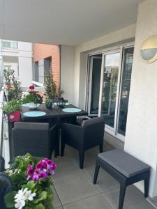 a patio with a table and chairs and flowers at Appartement haut standing F2 Rivetoile Strasbourg centre parking gratuit terrasse in Strasbourg