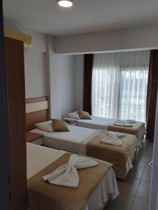 a hotel room with three beds and a window at Soleil Hotel in Kuşadası