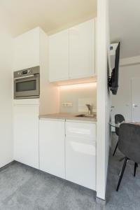 a kitchen with white cabinets and a table and a chair at Vienna Cube Apartments in Vienna
