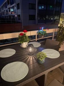 une table en bois avec des assiettes et des fleurs sur un balcon dans l'établissement Appartement haut standing F2 Rivetoile Strasbourg centre parking gratuit terrasse, à Strasbourg