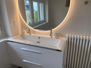 a bathroom with a sink with a mirror and a radiator at Villa Vieilles Vignes vue mer in Billiers