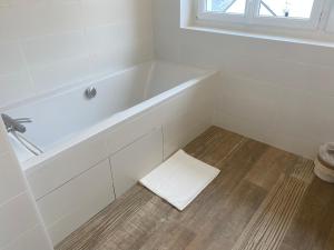 a bathroom with a white tub and a wooden floor at Villa Vieilles Vignes vue mer in Billiers