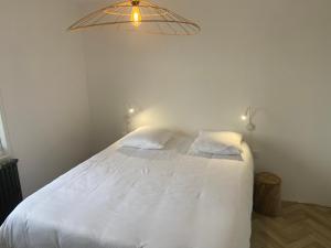 a white bed with two pillows and a light above it at Villa Vieilles Vignes vue mer in Billiers