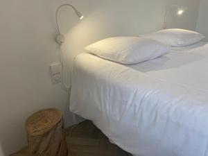 a bedroom with a bed with white sheets and a lamp at Villa Vieilles Vignes vue mer in Billiers