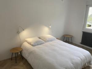 a bedroom with a large white bed with two tables at Villa Vieilles Vignes vue mer in Billiers