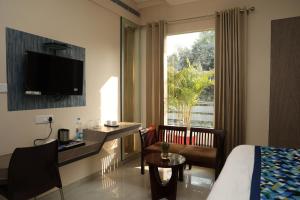 a hotel room with a bed and a desk and a window at Hotel Pinaka Inn in Lucknow