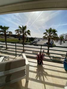 vistas a un balcón con un banco y palmeras en Atlantic Lodge, 1ª linha de praia!, en Costa da Caparica