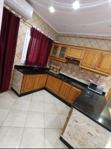 una cocina con armarios de madera y cortinas rojas en Résidence Amel en 'Aïn el Turk