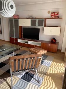 a living room with a glass table and a television at Atlantic Lodge, 1ª linha de praia! in Costa da Caparica