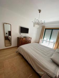 a bedroom with a large bed and a mirror at Atlantic Lodge, 1ª linha de praia! in Costa da Caparica