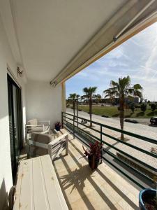 uma varanda com vista para o oceano e para as palmeiras em Atlantic Lodge, 1ª linha de praia! em Costa da Caparica