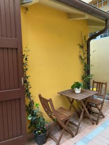 einen Tisch und Stühle neben einer gelben Wand in der Unterkunft Realkasa Belfiore Apartment in Bologna