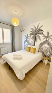 um quarto com uma grande cama branca com palmeiras na parede em La Douceur Roannaise - Parking privé proche gare em Roanne