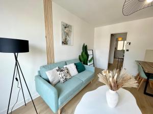 uma sala de estar com um sofá azul e uma mesa em La Douceur Roannaise - Parking privé proche gare em Roanne