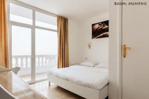 a white bedroom with a bed and a large window at Desert Moon in Cairo