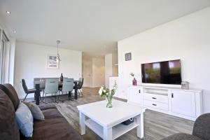 a living room with a couch and a tv and a table at Villa Petersen Ankerplatz 3 in Wangerooge