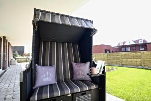 a black outdoor bench with purple pillows on a patio at Villa Petersen Ankerplatz 3 in Wangerooge