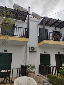 a white building with two balconies and two chairs at Erodios Apartments in Kalyves