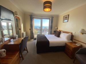 a hotel room with a bed and a desk and a window at The Riviera Hotel & Apartments - Alum Chine in Bournemouth