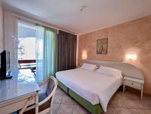 a bedroom with a bed and a desk and a window at Hotel Meridiana in Marina di Campo