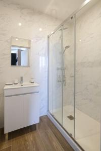 La salle de bains est pourvue d'une douche en verre et d'un lavabo. dans l'établissement Villa Forestière Studio Le Châtaignier, à Quincy-Voisins