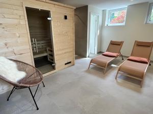 a living room with two chairs and a wall at Le Hêtre Rouge & spa in Barr