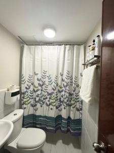 a bathroom with a toilet and a shower curtain at Condo Stay at Saekyung Looc in Lo-oc