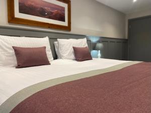 a bedroom with a large white bed with two pillows at The Old Gables in Brampton