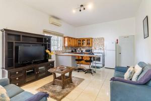 sala de estar con sofá azul y TV en Rose View Apartment en Montego Bay
